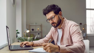 Man studying in a bright office with a laptop and notebook