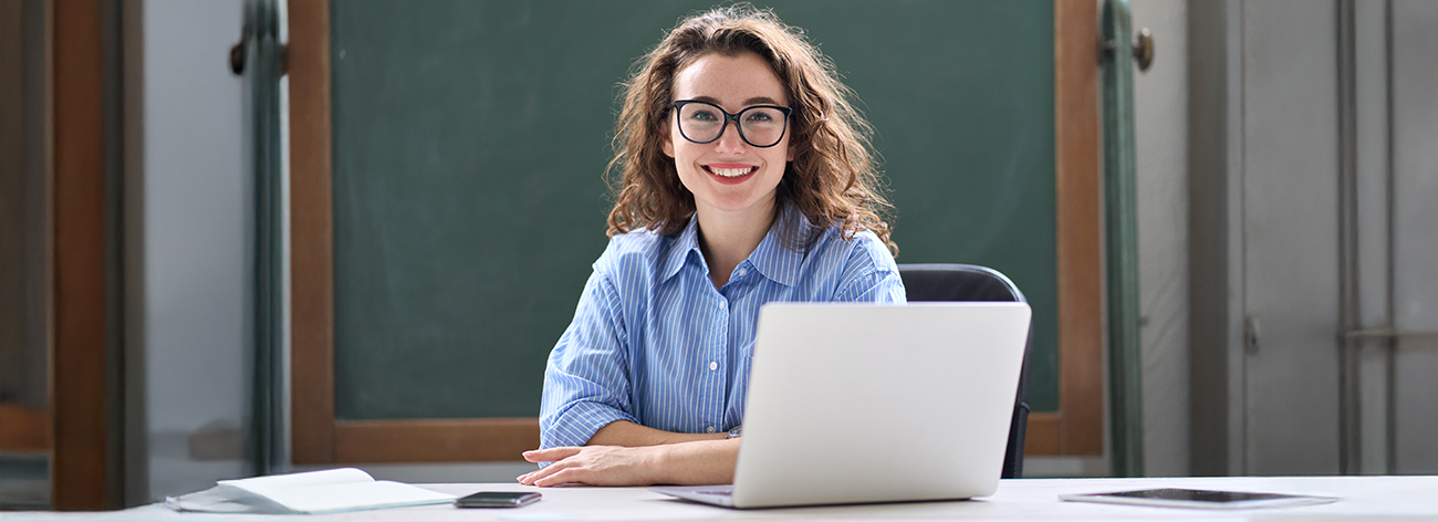 Woman in a blue dress shirt looks sitting in front of computer.