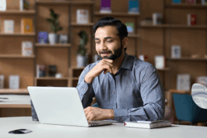 Man in a dress shirt looks at his computer in the office.