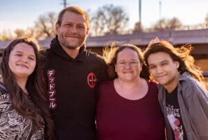 Kayla Baldwin smiles with family outdoors at golden hour near a stadium